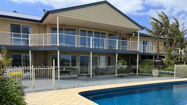 A two-story building with a swimming pool, outdoor seating, and a fenced patio area. - Resort Style Apartment (Ground Floor) - Pool & More. Pets Welcome. (Lakes Entrance)