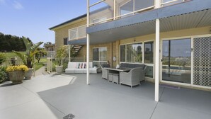 A modern house with a covered patio, outdoor furniture, and large windows. - Resort Style Apartment (Ground Floor) - Pool & More. Pets Welcome. (Lakes Entrance)