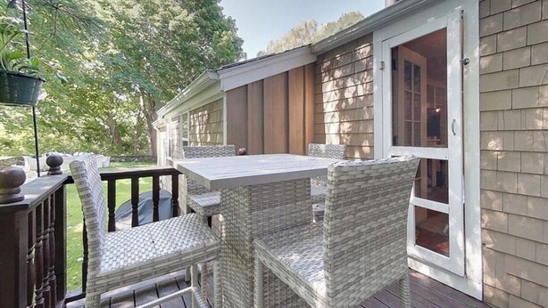 An outdoor patio with wicker furniture and a sliding glass door leading to a covered area. - Quintessential Cottage near beaches and Newport center. (Middletown)