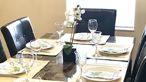 Een eettafel voor vier gedekt, met borden, bestek en wijnglazen.