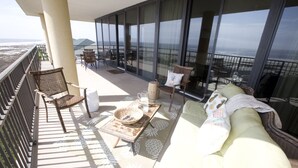 Un balcón con sofá, sillas, una mesa y vista al océano.