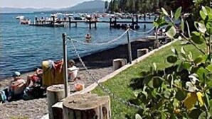 A lakeside view with boats docked, a wooden fence, and greenery. - MODERN LOG CABIN-HOT TUB-TAHOE PARK BCH ACCESS (Tahoe City)