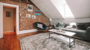 Una habitación estilo loft con paredes de ladrillo visto, techo inclinado y tragaluces.