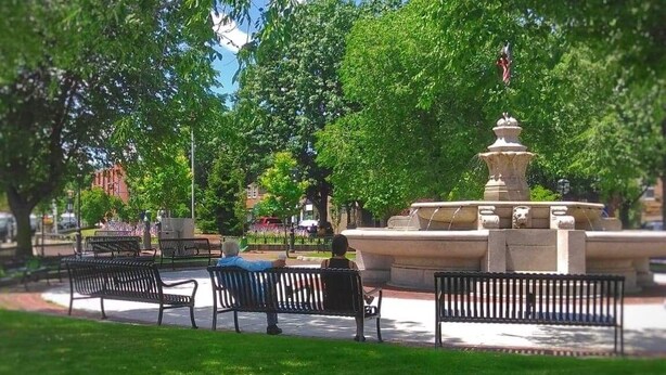 Un parque con una fuente, bancos y árboles.