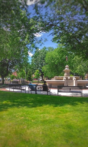 Ein Park mit einem Brunnen, Bänken und Bäumen.