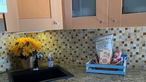 A kitchen with wooden cabinets, a granite countertop, a sink, a stove, and a vase with yellow flowers.