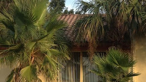 A two-story building with a tiled roof, surrounded by palm trees and a well-maintained lawn.