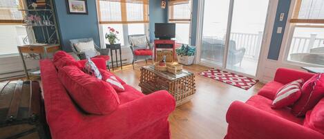 A living room with red sofas, a wooden coffee table, wicker baskets, and a TV on a stand.