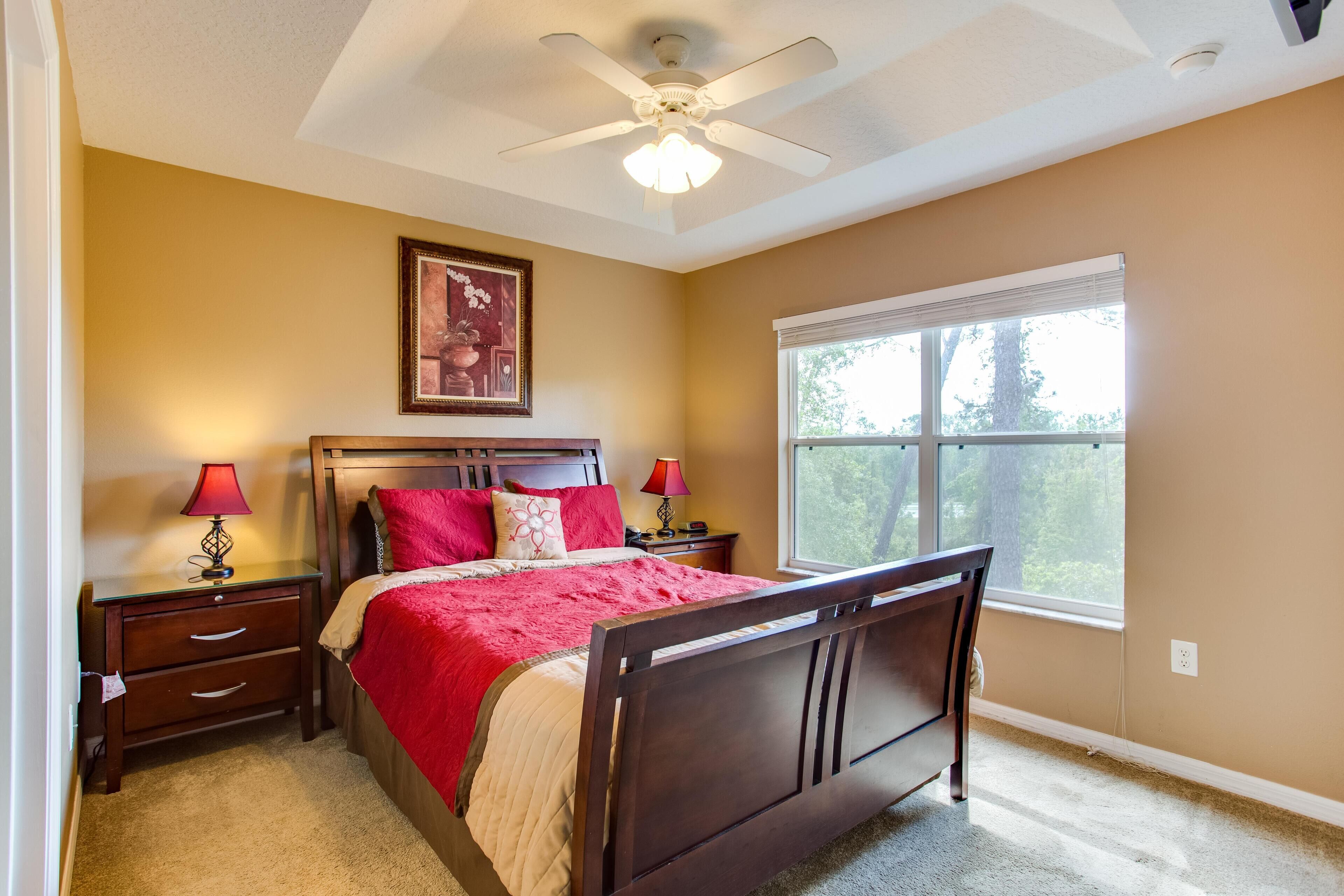 A bedroom with a bed, nightstands, a ceiling fan, a window, and a framed picture on the wall.