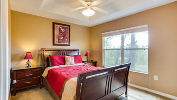 A bedroom with a bed, nightstands, a ceiling fan, a window, and a framed picture on the wall.