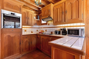 A kitchen with wooden cabinets, a stainless steel refrigerator, a microwave, and a coffee maker.