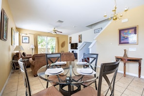 A dining area with a glass table, chairs, and a chandelier.