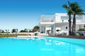 A modern two-story building with a pool, palm trees, and lounge chairs. - Villa Orizzonte, Marina Di Modica (Marina di Modica)