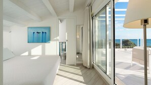 A modern bedroom with a large bed, a painting, a bathroom, and a balcony with a view of the sea. - Villa Orizzonte, Marina Di Modica (Marina di Modica)