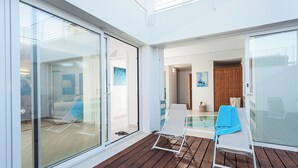 A modern outdoor area with a wooden deck, glass sliding doors, and a pool area. - Villa Orizzonte, Marina Di Modica (Marina di Modica)