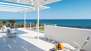 A modern outdoor terrace with white furniture, a fruit bowl, and a view of the sea. - Villa Orizzonte, Marina Di Modica (Marina di Modica)