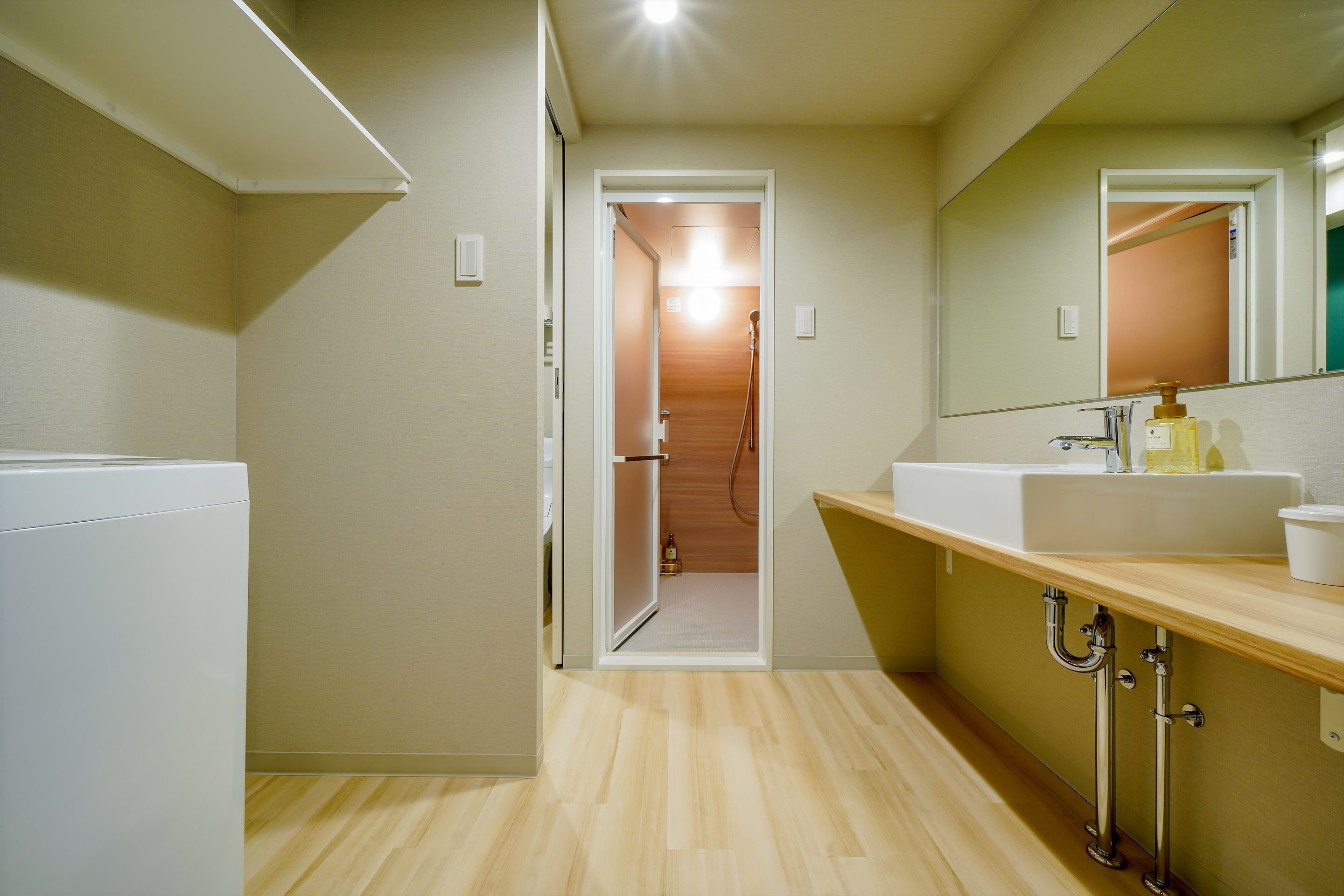 A modern bathroom with a wooden vanity, a white sink, and a mirror.