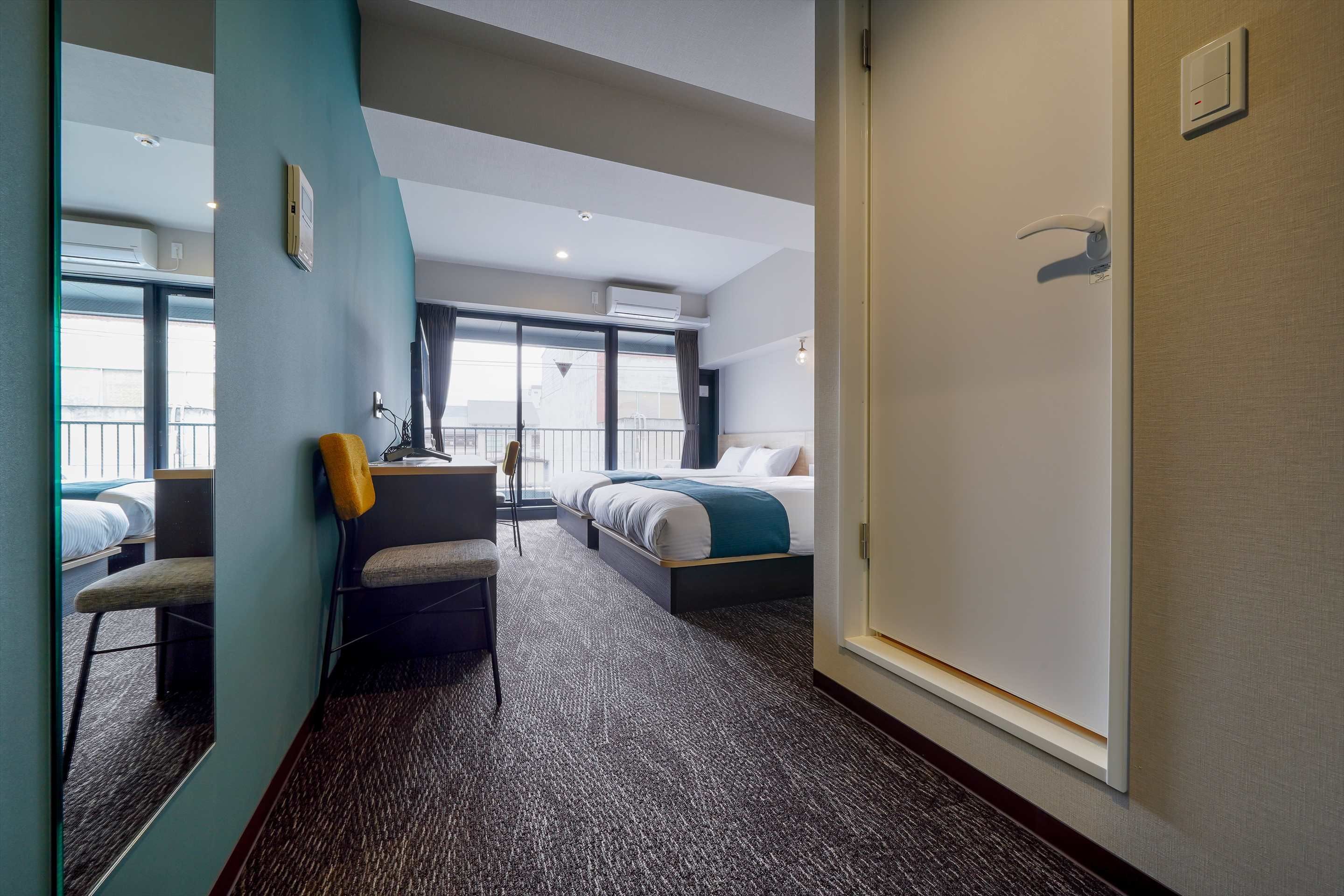 Une chambre d’hôtel avec un lit, un bureau, une chaise et une grande fenêtre.