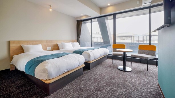 A hotel room with two beds, a small table, and chairs, a large window with a view, and a modern design. - RESI STAY HEART (Kyoto)