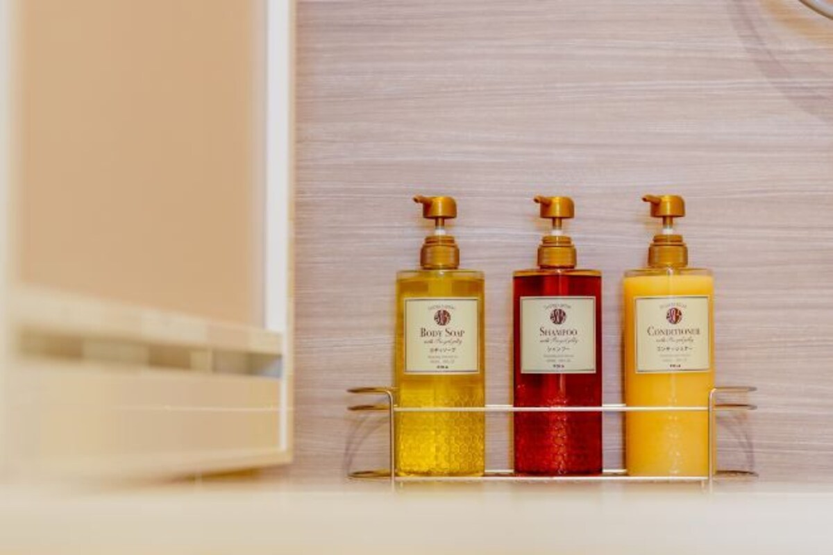 Three bottles of body care products on a clear shelf.
