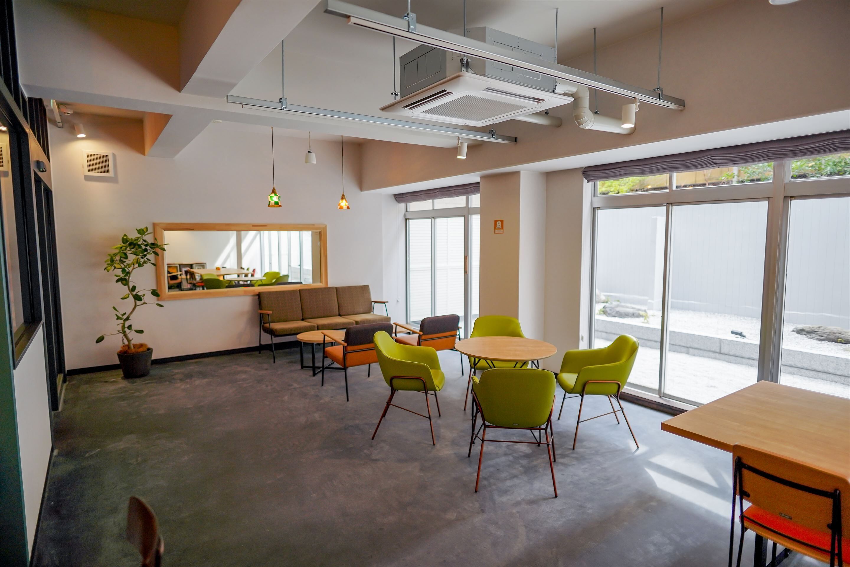 A modern office space with a large window, a sofa, a dining table, and several chairs.