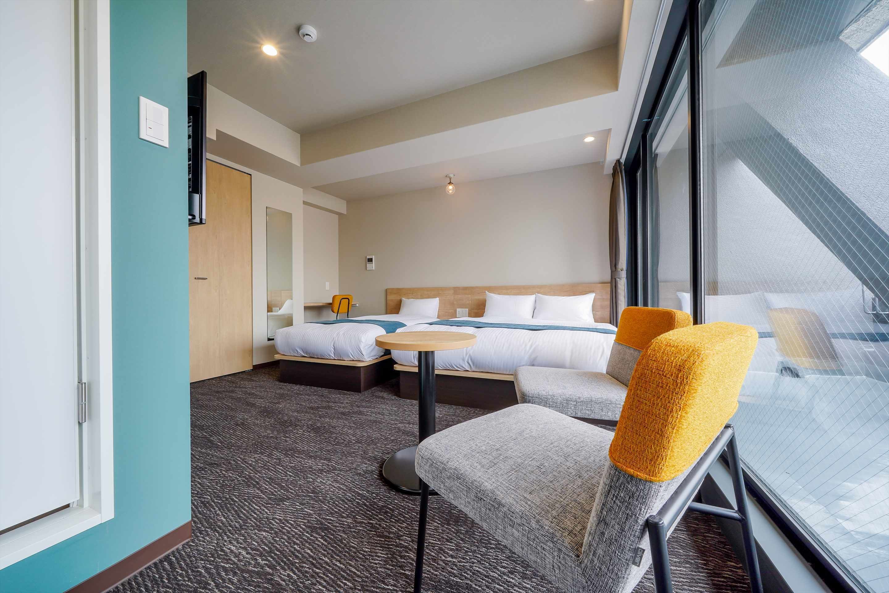 A hotel room with a bed, two bedside tables, a small round table, and a window with a view.