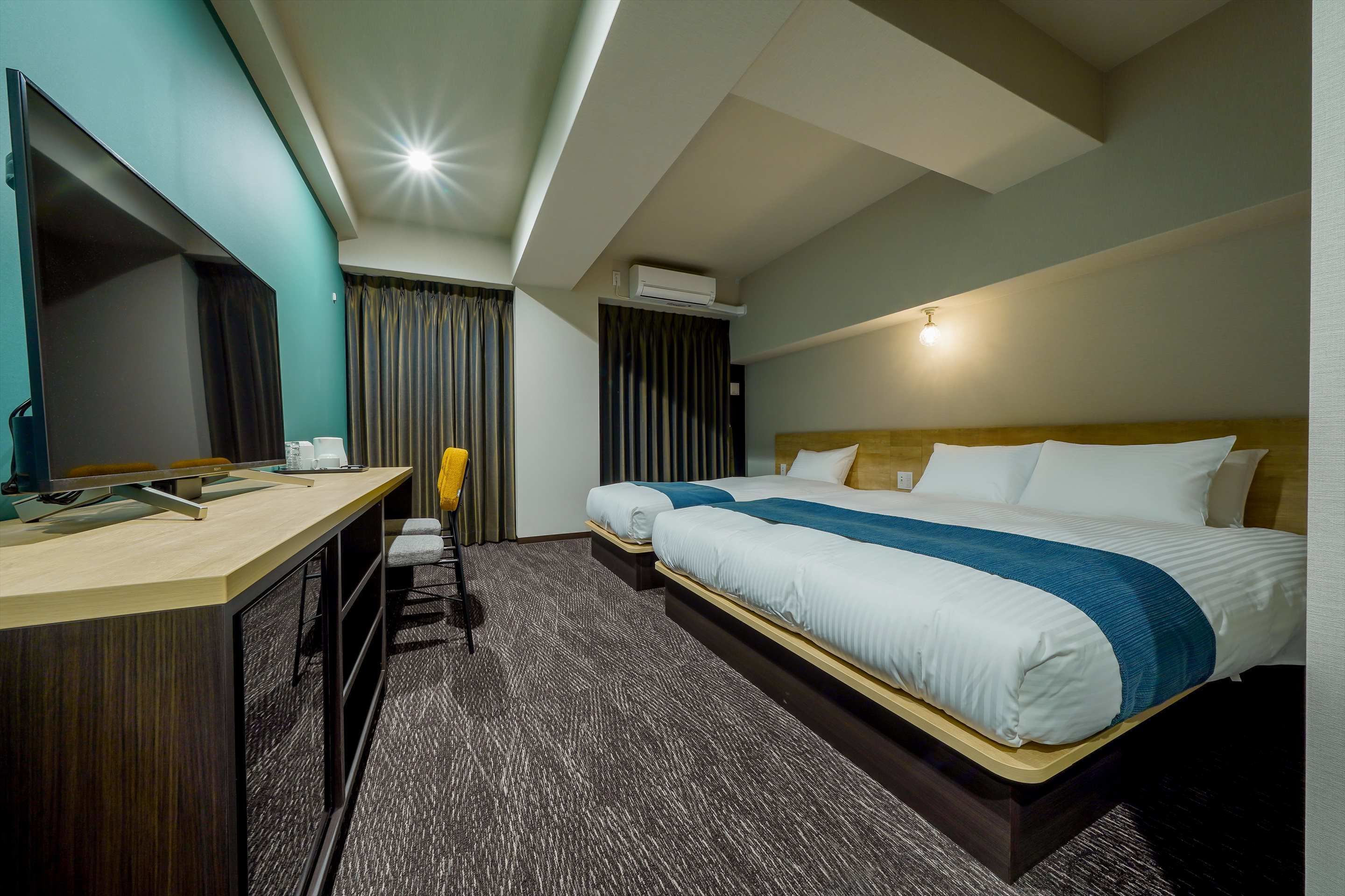 Ein Hotelzimmer mit einem Bett, einem Schreibtisch, einem Stuhl und einer Klimaanlage.