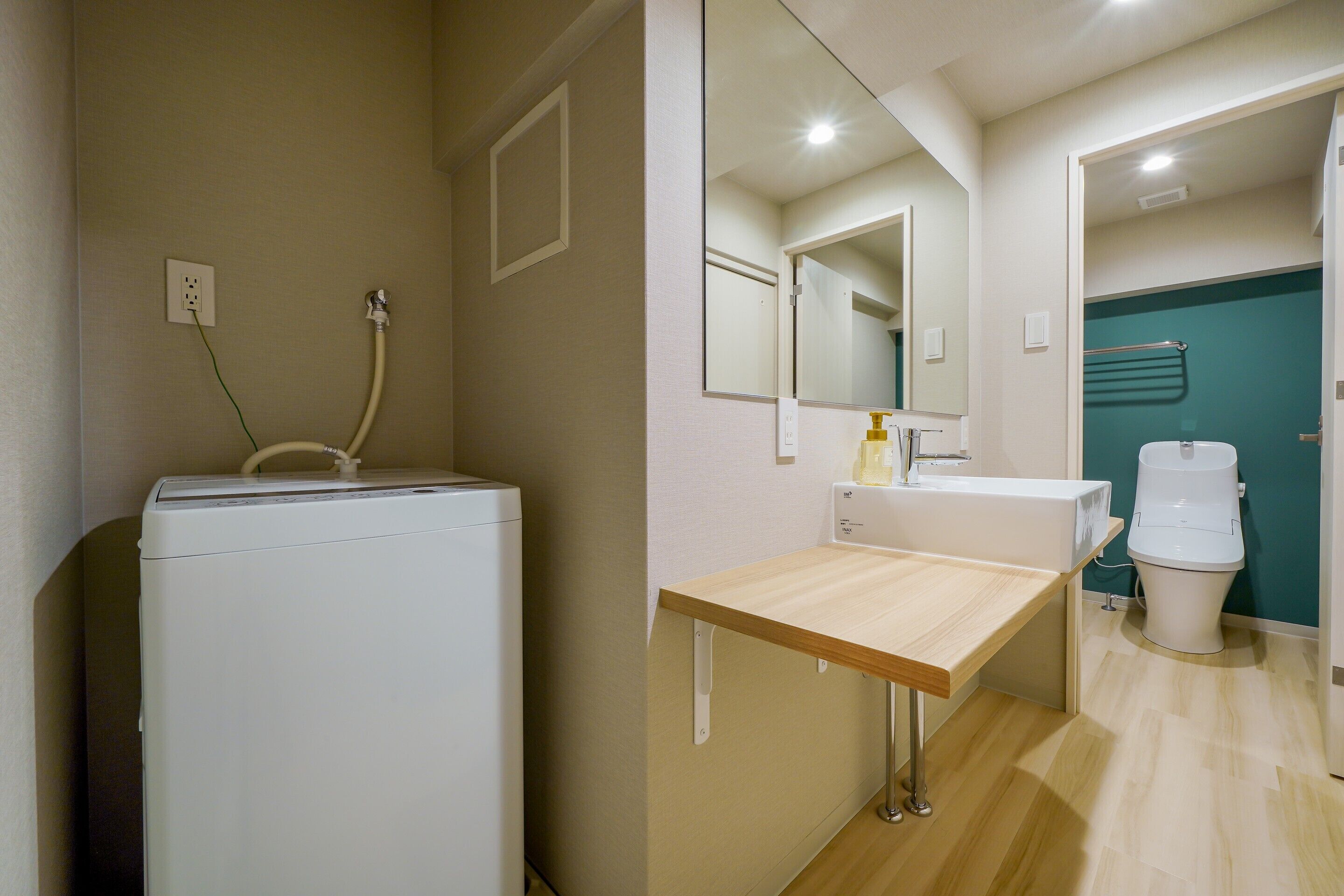 Un bagno compatto con lavatrice, lavandino e servizi igienici.