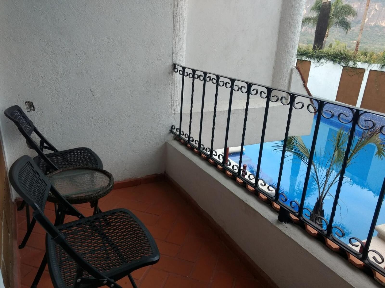 Un balcon avec une rambarde en métal, une chaise et une vue sur une piscine.