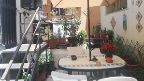 A patio area with a round table, chairs, potted plants, a ladder, and a large umbrella. - Catania House single apartment sleeps 4 near the new Garibaldi  (Catania)