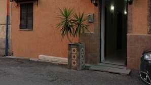A residential building with a tiled roof, a small entrance with a door, and a potted plant in front. - Catania House single apartment sleeps 4 near the new Garibaldi  (Catania)