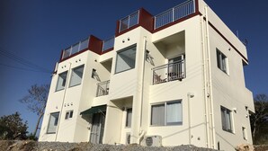 A multi-story building with balconies, large windows, and a flat roof. - Seabreeze Kouri (Nakijin)