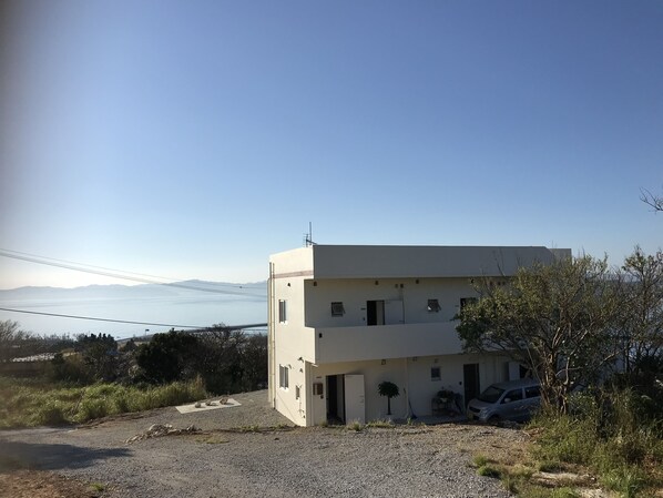 Un edificio de dos pisos con un camino de grava y un automóvil estacionado.