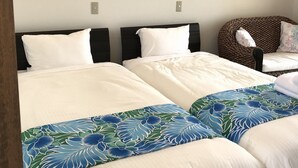 A hotel room with two beds, a chair, and wall-mounted lights. - Seabreeze Kouri (Nakijin)