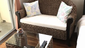 A cozy living area with a woven sofa, a glass coffee table, and a remote control on the table. - Seabreeze Kouri (Nakijin)
