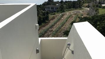 A staircase leading to a balcony overlooking a coastal landscape with a view of the sea and distant mountains.