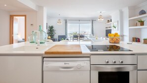 Cocina moderna con armarios blancos, encimera de madera, lavavajillas Balay y horno de acero inoxidable.
