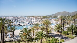 Un puerto deportivo con numerosas embarcaciones amarradas, rodeado de palmeras y un cielo despejado.