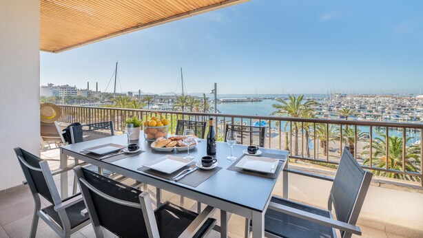 Mesa para dos con vista a un puerto deportivo y al paisaje urbano.