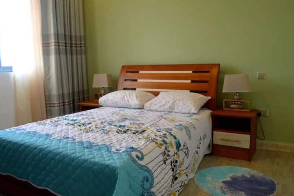 A bed with a floral bedspread, two bedside tables with lamps, and a round rug on the floor.