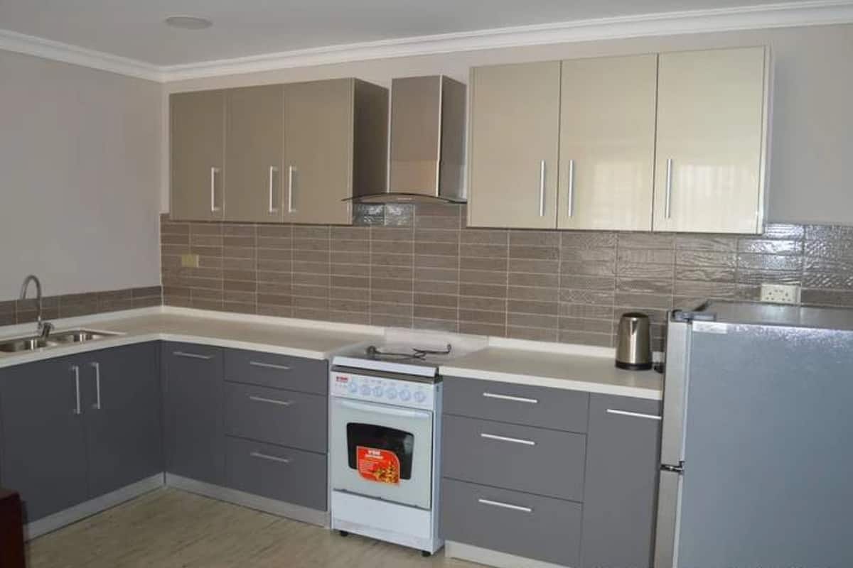 A compact kitchen with grey cabinets, a built-in oven, a sink, and a refrigerator.