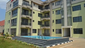A multi-story building with a swimming pool, balconies, and a flat roof. - Serene Crest Apartments (Kigali)