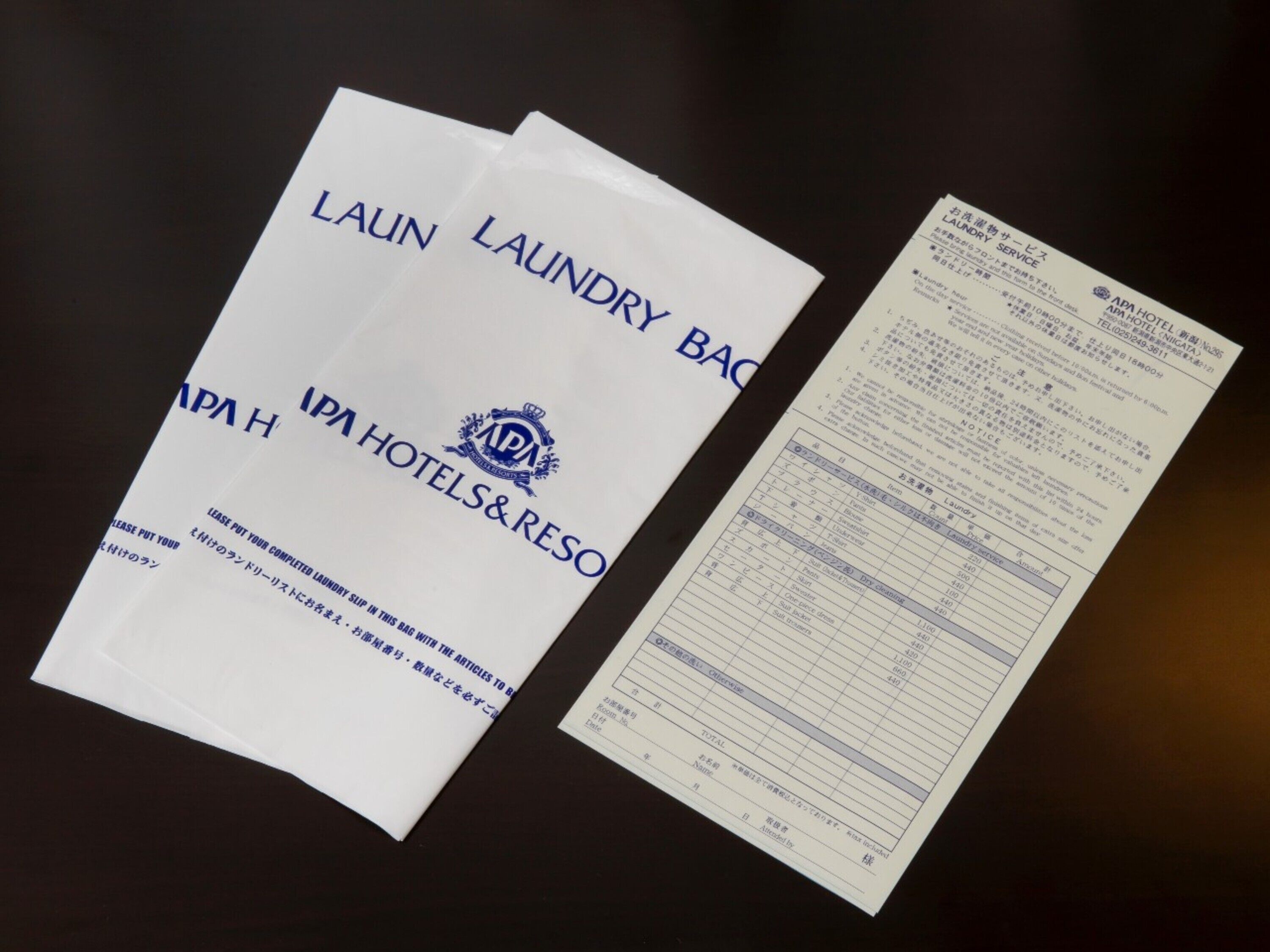 Un ensemble de sacs blancs sur lesquels sont imprimés les mots « SAC À LINGE » et « IPA HOTELS & RESO », ainsi qu’un reçu de service de blanchisserie.
