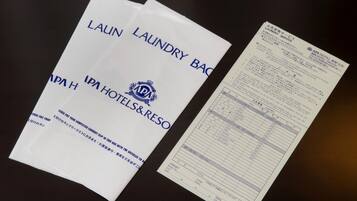 Un ensemble de sacs blancs sur lesquels sont imprimés les mots « SAC À LINGE » et « IPA HOTELS & RESO », ainsi qu’un reçu de service de blanchisserie.