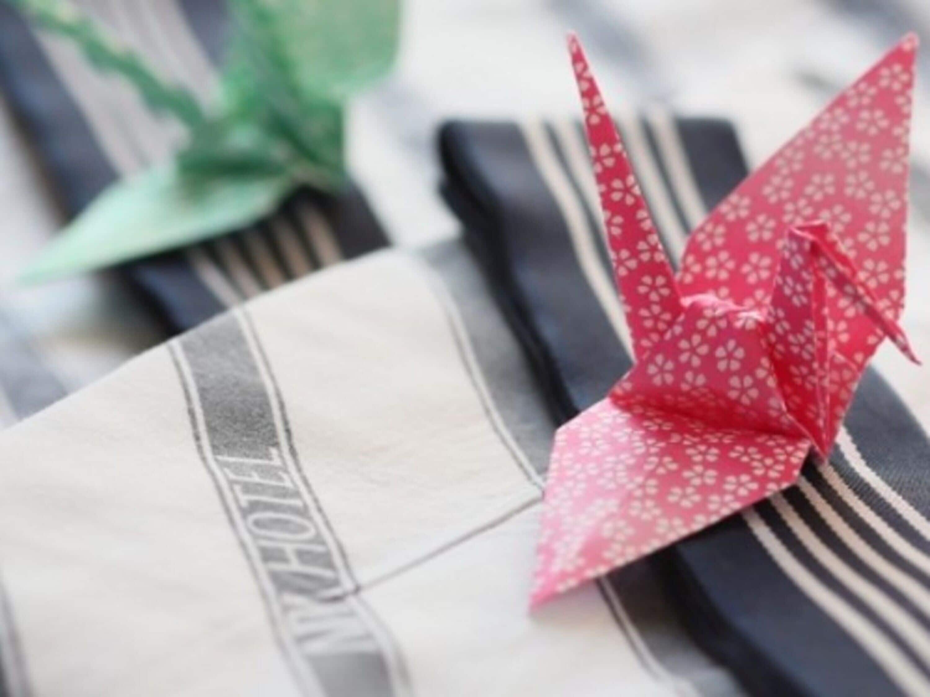 A striped fabric with a red origami crane on top.