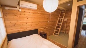 A wooden-paneled room with a bed, a ladder, and an air conditioning unit. - Kyoto Tanbaguchi Classic Japanese House (Kyoto)