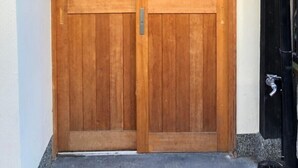 A traditional wooden door with vertical slats, a small light fixture above, and a weather vane on the right. - Kyoto Tanbaguchi Classic Japanese House (Kyoto)
