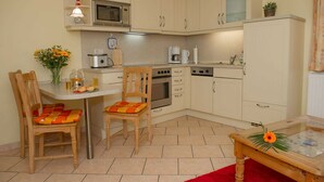 Una cocina compacta con comedor, que incluye una mesa, sillas y un microondas.