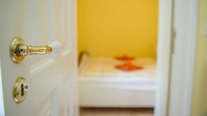 Una puerta con cerradura y ojo de cerradura, que da a una habitación con pared amarilla y un objeto blanco en el suelo.