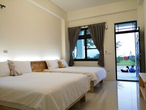 A bedroom with two beds, a window with curtains, a teddy bear on one bed, and a view of the outside. - Rural Scenary Villa (Taitung)